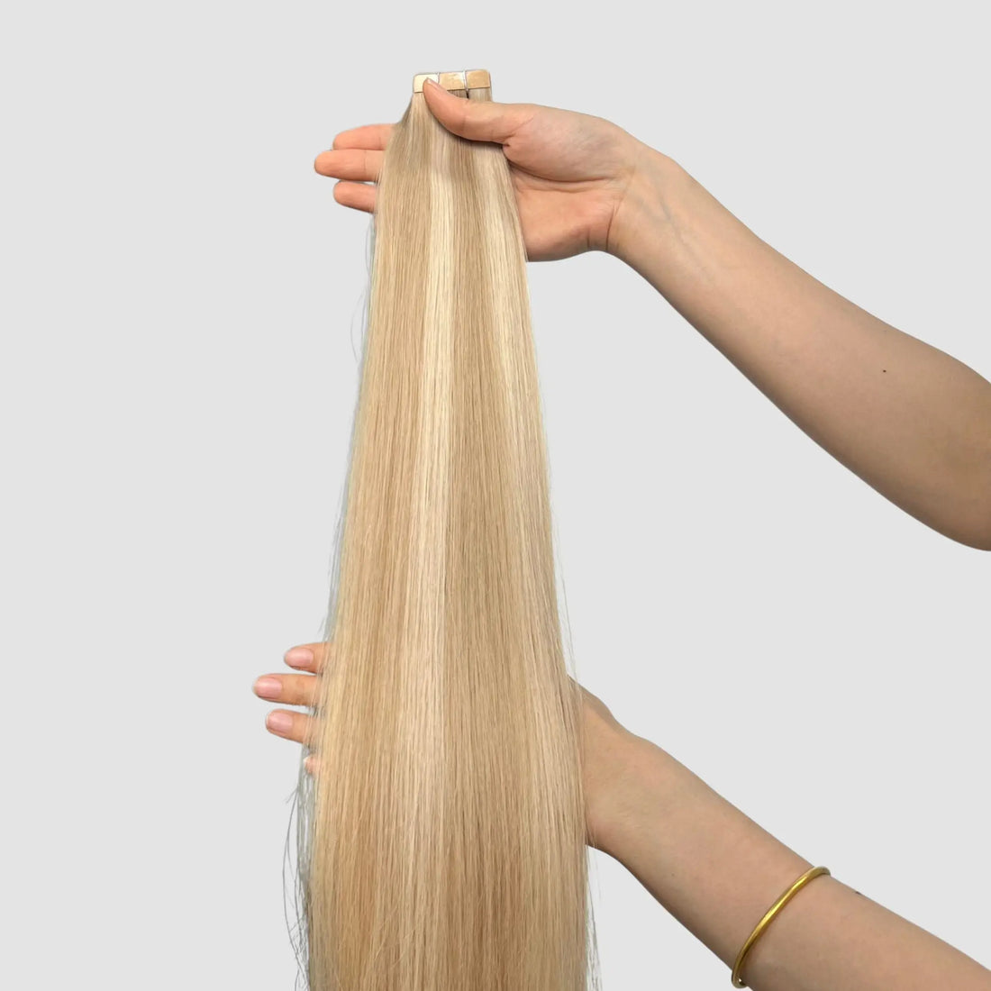 Rakt löshår i nyans 18/60A, beige blond balayage, hållet framför en ljus bakgrund